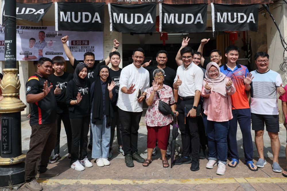 Muda president Syed Saddiq Syed Abdul Rahman with residents of Kampung Cina in Kuala Terengganu after the launch of the party’s operations rooms, July 26, 2023. With him are deputy president Amira Aisya Abd Aziz and the party’s information chief Luqman Long, who will contest the Bandar state seat. — Bernama pic 