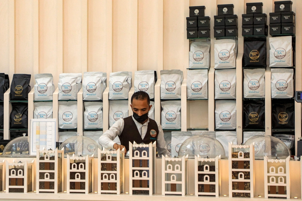 A speciality coffee shop employee packages and sells coffee at the shop's counter. — AFP pic