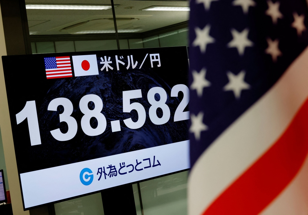 A monitor displaying the current Japanese Yen exchange rate against the US dollar is seen next to a US national flag at the foreign exchange trading company Gaitame.com in Tokyo, Japan, July 28, 2023. — Reuters pic