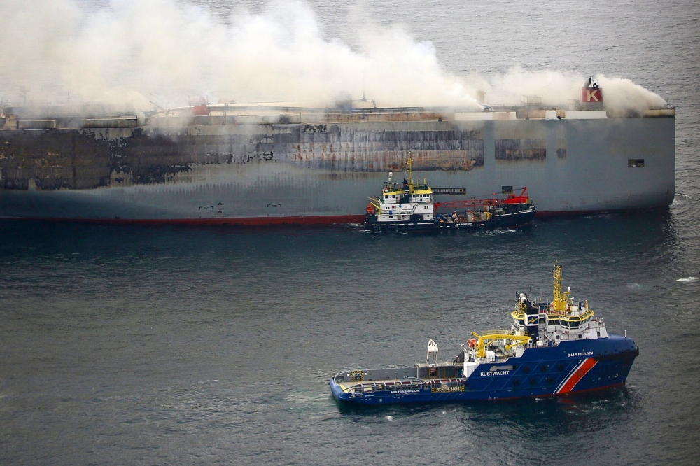 This handout photograph taken on July 28, 2023 from the Coast Guard plane and released on July 29, 2023 by the Dutch coastguards, shows a Multrasalvor 4 rescue vessel sailing next to a fire aboard the Panamanian-registered car carrier ship Fremantle Highway. — Picture by Handout / Netherlands Coastguards / AFP