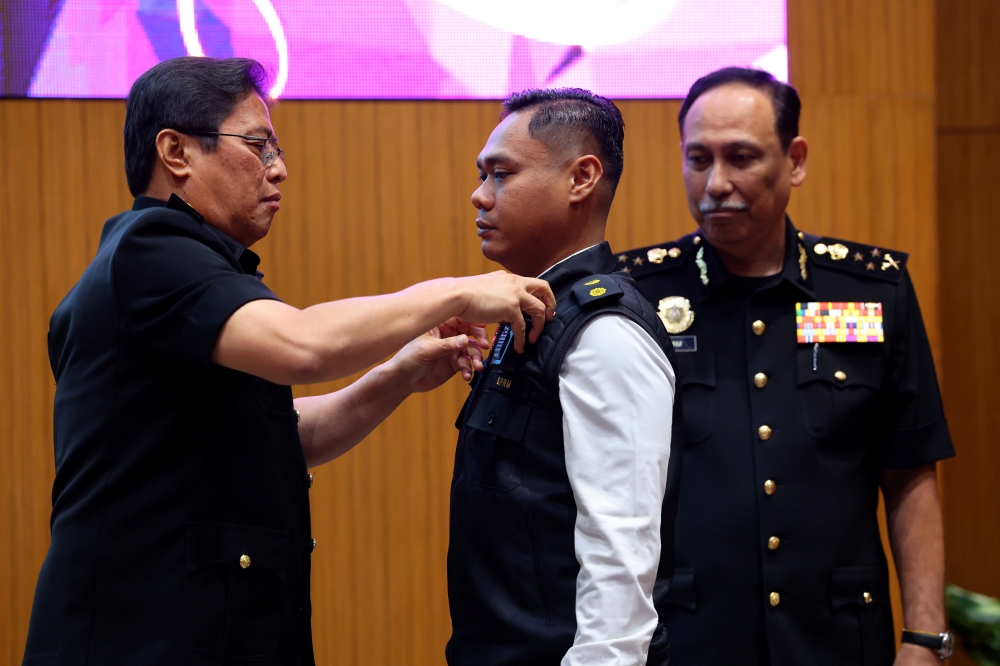 MACC chief commissioner Tan Sri Azam Baki fixes a body-worn camera on an officer at the launch of the BWC and MACC jacket in Putrajaya, July 31, 2023. — Bernama pic 