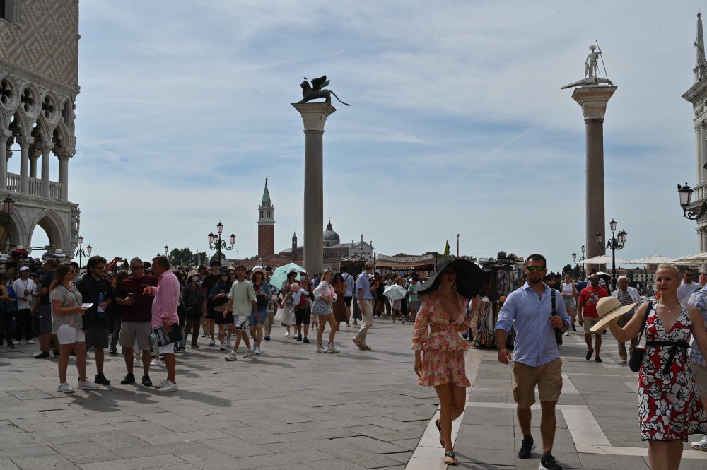 A view taken on July 31, 2023 shows tourists walk across St. Mark's square in Venice.  — AFP pic