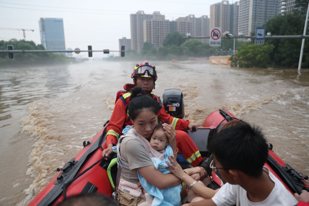 Rescue workers evacuate residents stranded by floodwaters with a boat, following heavy rainfall in Zhuozhou, Hebei province. — Reuters pic
