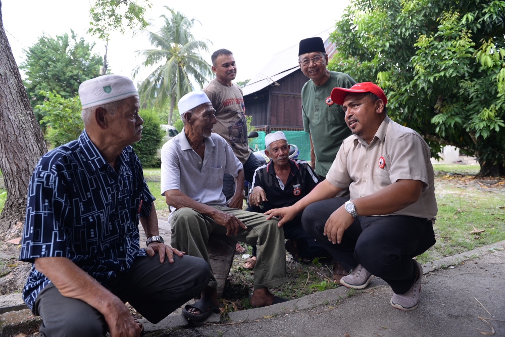 PH Bayan Lepas candidate Azrul Mahathir Aziz (right) talks to a group of villagers at Kampung Tengah during his campaign in Teluk Kumbar, August 3, 2023. — Picture by KE Ooi