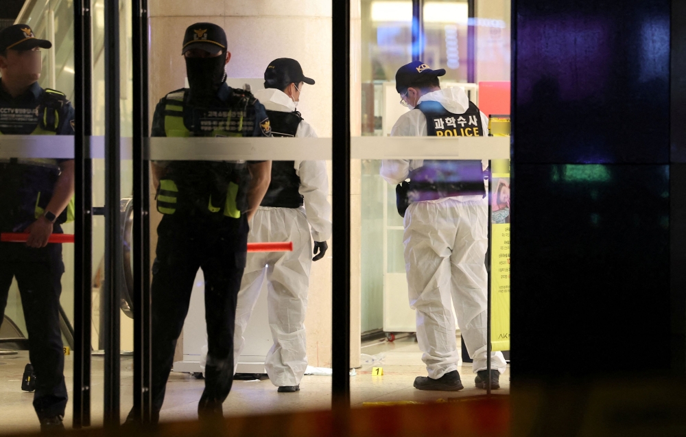 Police examining the crime scene where nine people were stabbed and five hit by car. — Reuters pic
