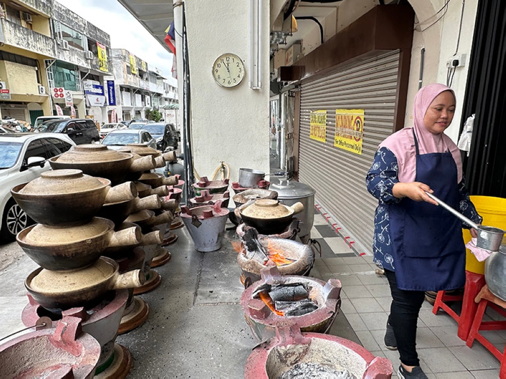 Nona cooks up your claypot chicken rice over a hot charcoal fire