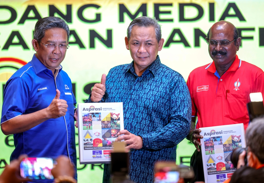 Negeri Sembilan PH chairman Datuk Seri Aminuddin Harun (centre) and state Umno Liaison Committee chairman Datuk Seri Jalaluddin Alias (left) pose with the Pakatan Harapan and Barisan Nasional manifesto during its launch in Seremban August 6, 2023. — Bernama pic