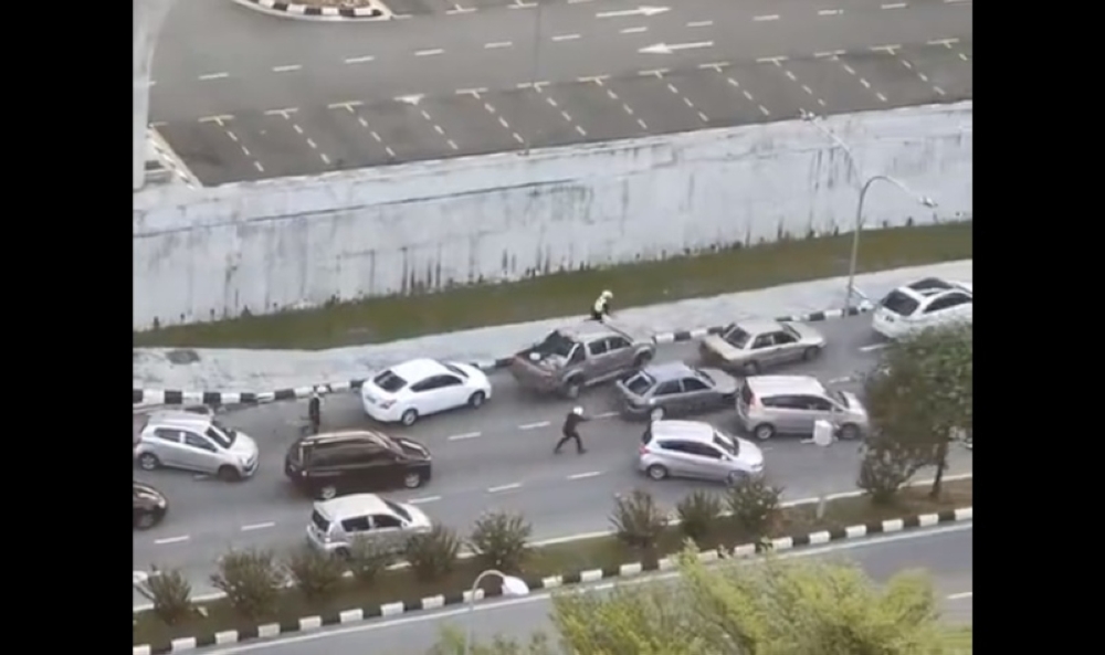 A video screengrab showing policemen in pursuit of the Proton Wira and shooting at its tyres. — Screengrab from Twitter/Bernama 