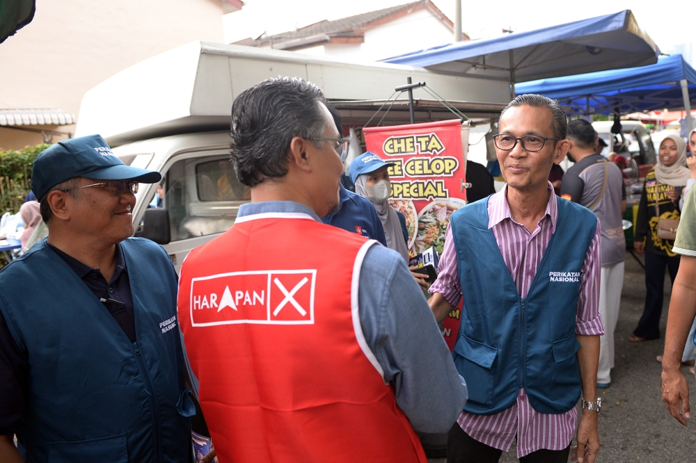 PH Batu Maung candidate Prof Datuk Mohamad Abdul Hamid and PN Batu Maung candidate Azahari Aris (right) bump into each other during their walkabout at the Bukit Gedung night market, Penang, August 7, 2023. — Picture by KE Ooi