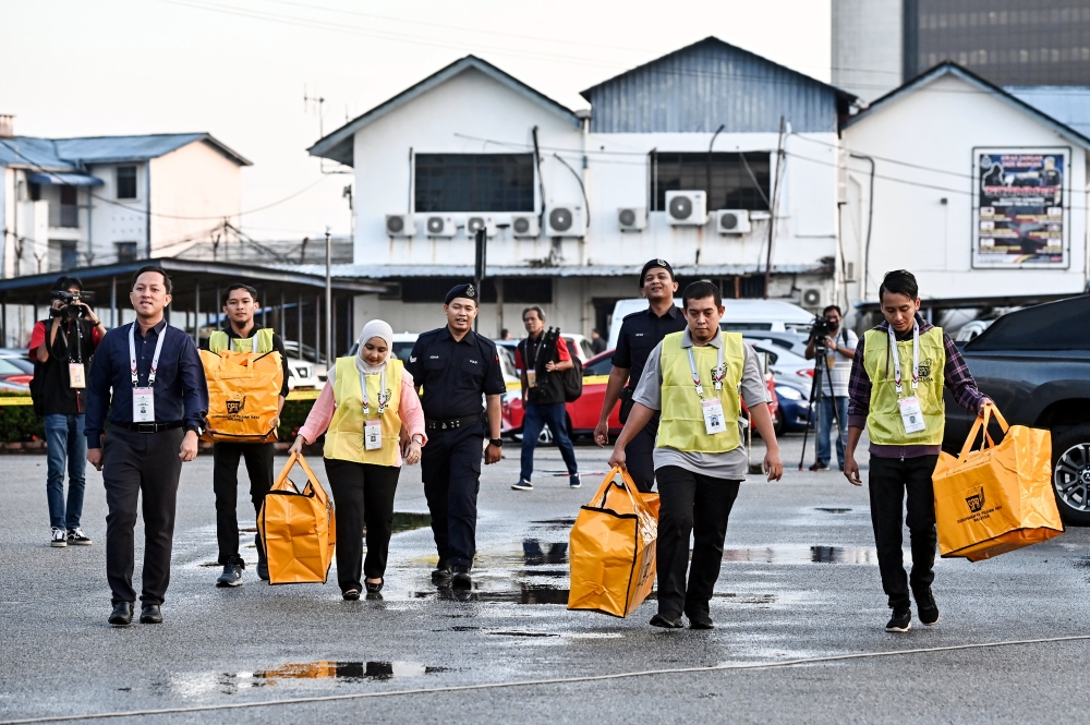 Election Commission personnel with empty ballot boxes are escorted by police officers into the early voting centre located at the Terengganu police contingent headquarters in Kuala Terengganu August 8, 2023. — Bernama pic