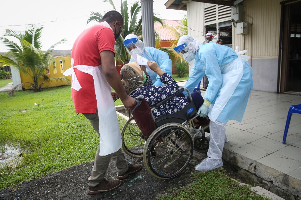 File picture of Health workers carrying a woman in a wheelchair to be tested for Covid-19 at the Dewan Masyarakat Taman Meru 3 in Klang December 2, 2020. KPWKM, in a statement today, said another finding was the absence of ramps for the use of wheelchair-bound PwD, in addition to ramps that are quite steep and which do not meet MS1184 standards. — Picture by Yusof Mat Isa
