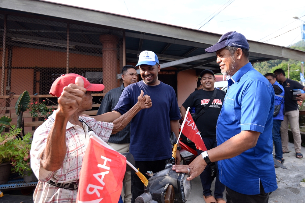 Barisan Nasional candidate Ahmad Zaki Shah Shah Headan and his father, former Telok Bahang assemblyman Datuk Shah Headan, talk to a voter during their walkabout in Sungai Rusa, Penang, August 9, 2023. — Picture by KE Ooi