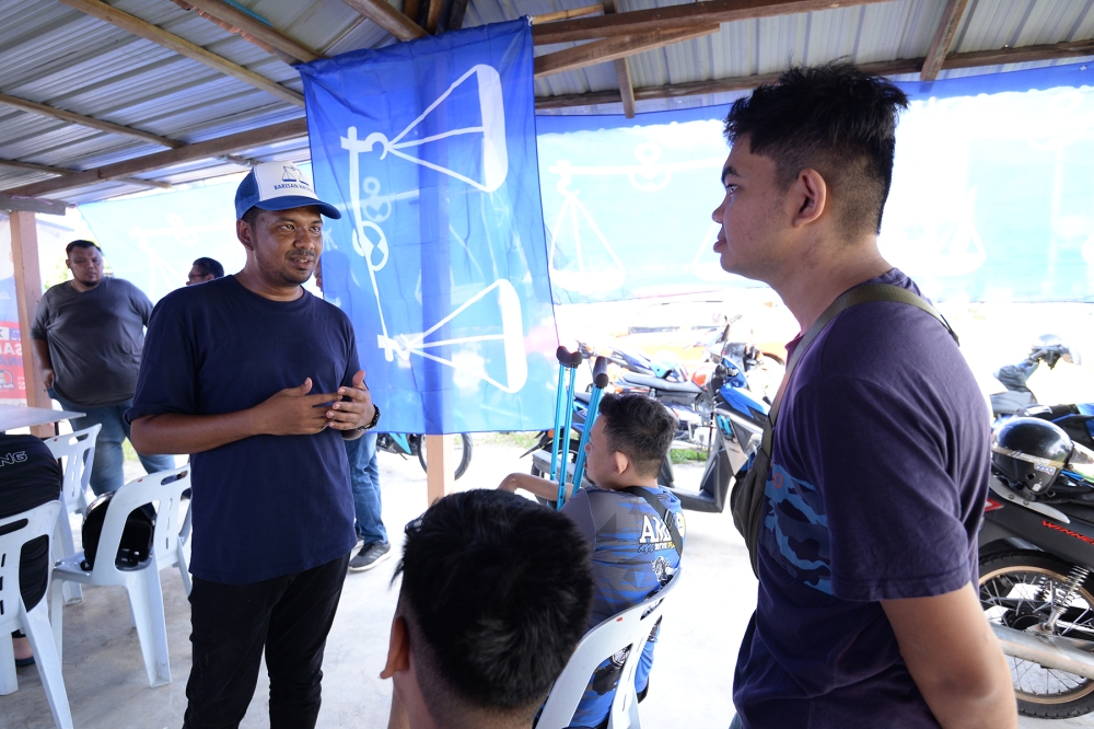 Ahmad Zaki talks to young voters during his walkabout campaign in his constituency in Teluk Bahang, Penang, August 9, 2023. — Picture by KE Ooi