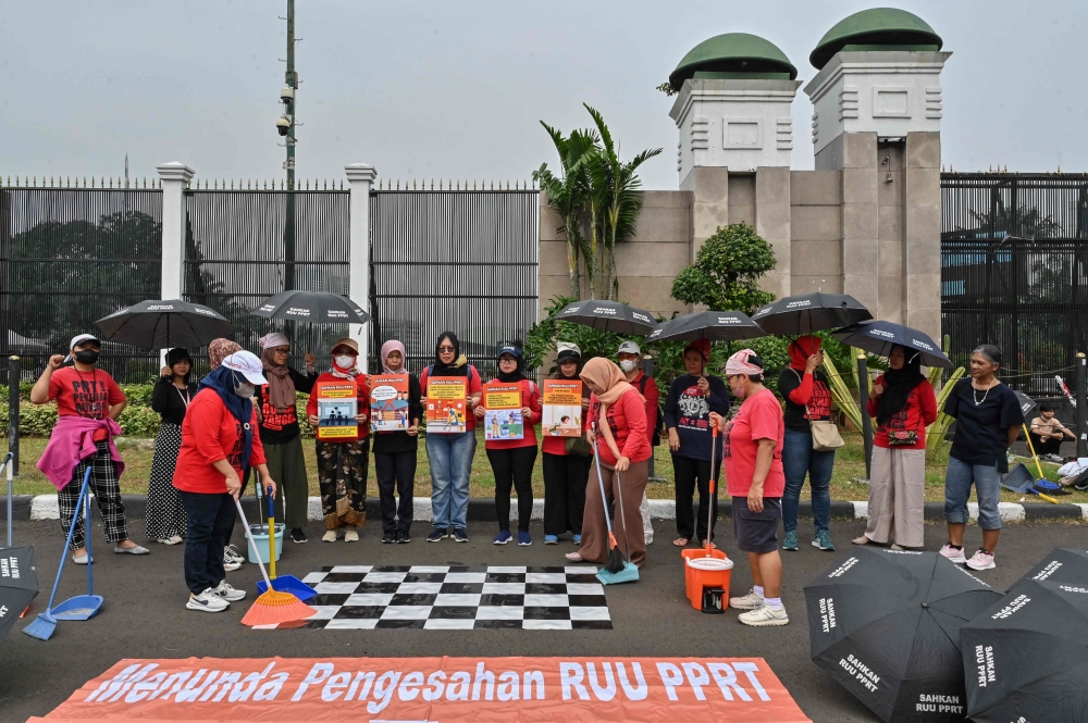 Demonstrators holding a theatrical protest demanding parliament to pass a law to protect domestic workers in Indonesia. — AFP pic