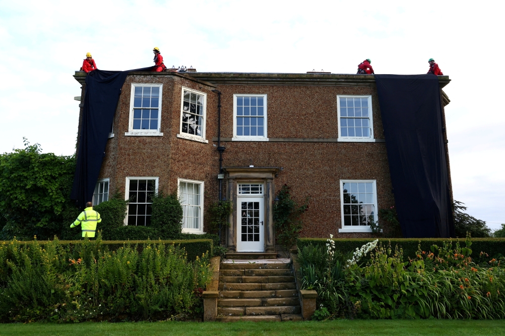 Greenpeace activists cover British Prime Minister Rishi Sunak's £2m manor house with oil-black fabric in protest of his backing for a major expansion of North Sea oil and gas drilling amidst a summer of escalating climate impacts, in Yorkshire, Britain August 3, 2023. — Greenpeace handout via Reuters
