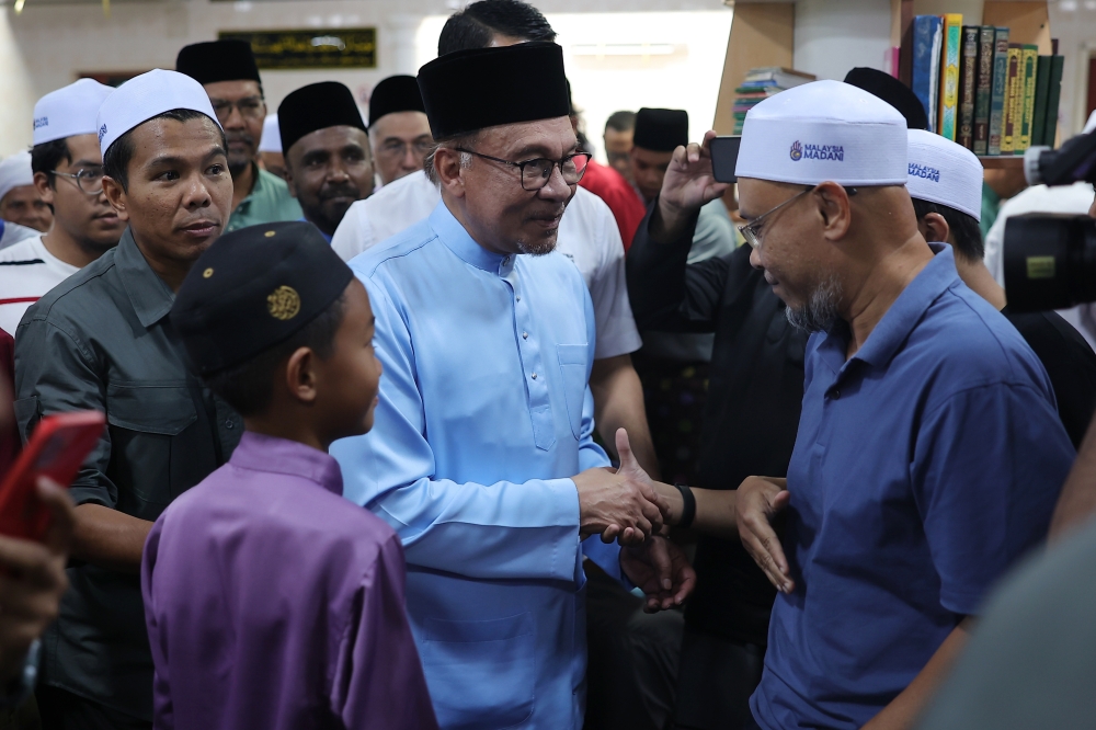 Prime Minister Datuk Seri Anwar Ibrahim (centre) shaking hands with the congregation after finishing Friday prayers at the Qaryah Mosque in Kampung Perlis, Balik Pulau, August 11, 2023. — Bernama pic
