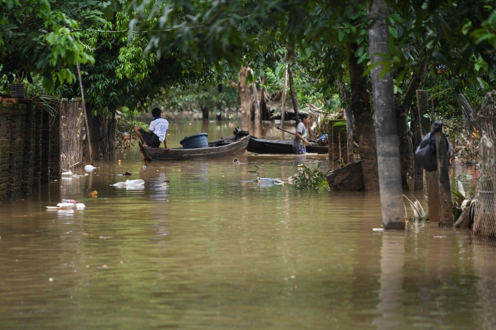 A man sits on the his wooden boat on a flooded street in Bilin township, in Myanmar’s Mon state, on August 11, 2023. — AFP pic