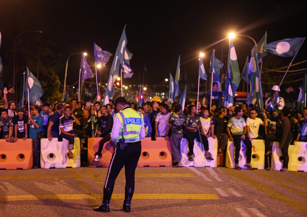 Police monitor the situation as PAS supporters gather in front of the official vote-counting centre at the Kijal Civic Hall in Terengganu, August 12, 2023. — Bernama pic 