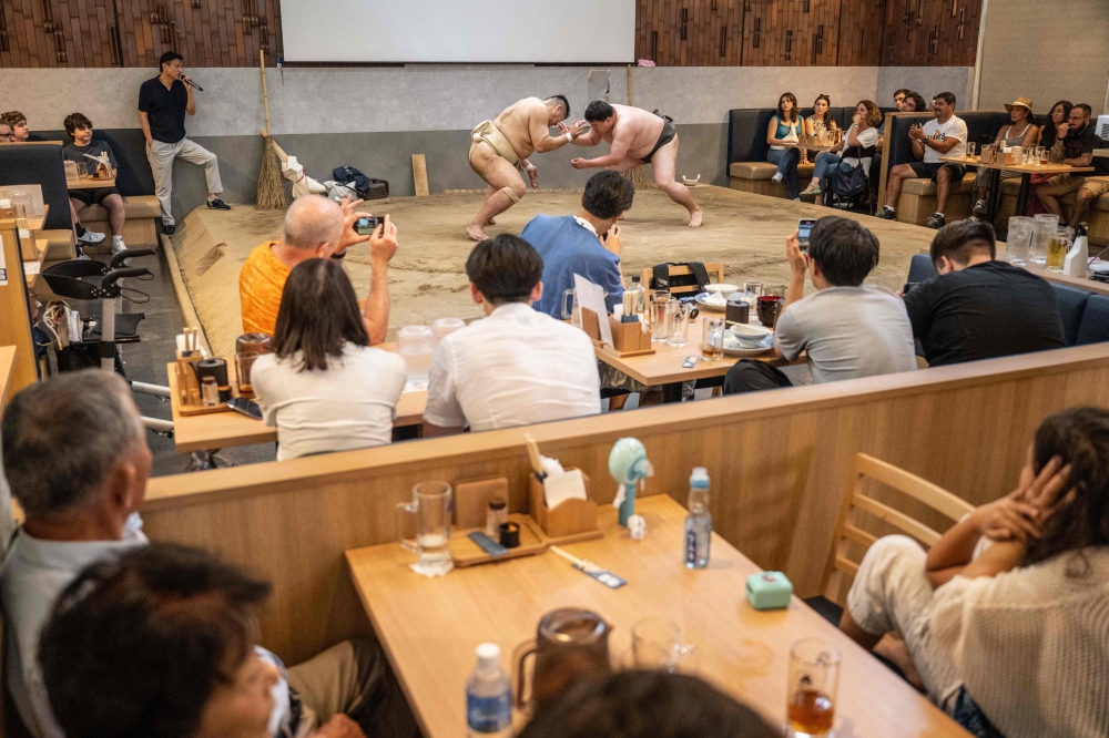 Former sumo wrestlers taking part in a demonstration match in front of tourists from abroad at the Yokozuna Tonkatsu Dosukoi Tanaka restaurant in Tokyo. — AFP pic