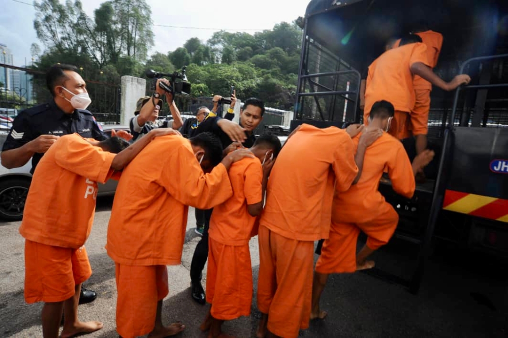 Policemen escorting the seven secondary school students, aged between 14 and 17, at the court complex compound in Johor Baru, August 16, 2023. — Picture by Ben Tan