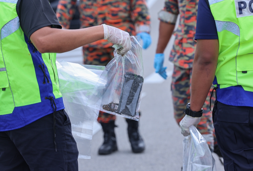 Police carry personal belongings of victims found at the site of the plane crash in Bandar Elmina, Shah Alam, August 18, 2023. — Bernama pic 