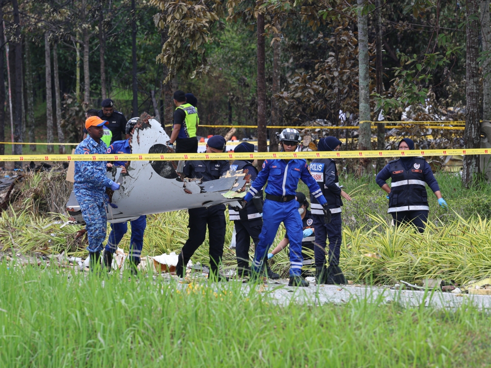 Members of the security forces carry a piece of the crashed private jet from the crash site in Elmina, Shah Alam August 18, 2023. — Bernama pic
