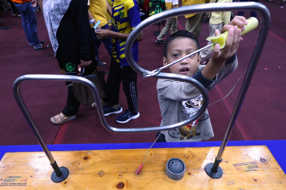 Seven-year-old Umar Al Fateh Abd Razak tries one of the activities at the ‘Kembara Sains Langkawi’ programme August 19, 2023. — Bernama pic