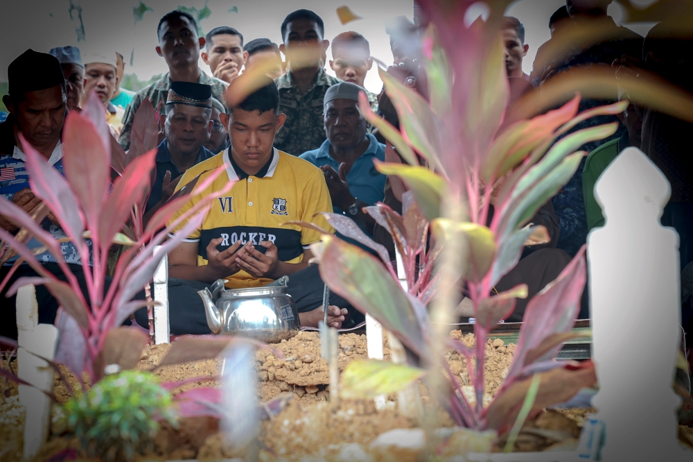 Muhammad Sharul Sharipuddin performs prayers after the burial of his father Sharipuddin Shaari at the Majid Jamek Sultan Hisamuddin cemetery in Bandar Baru Salak Tinggi, Sepang August 20, 2023. — Bernama pic