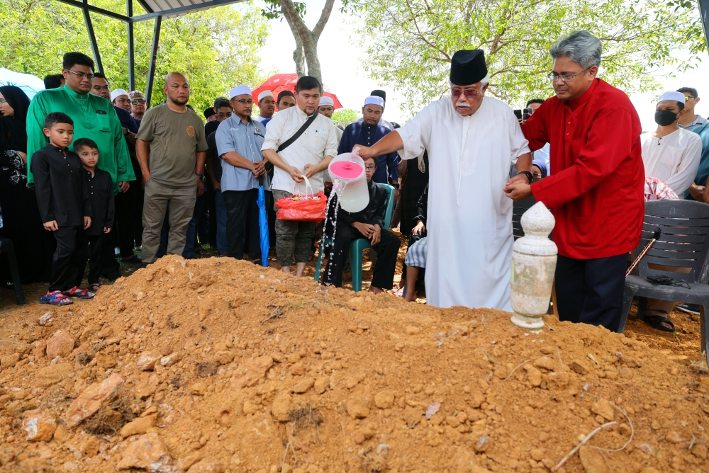 Late pilot Heikal Aras’ father Abdul Azim sprinkles rose water onto his grave after his burial at the Precinct 20 Muslim Cemetery in Putrajaya August 20, 2023. — Bernama pic