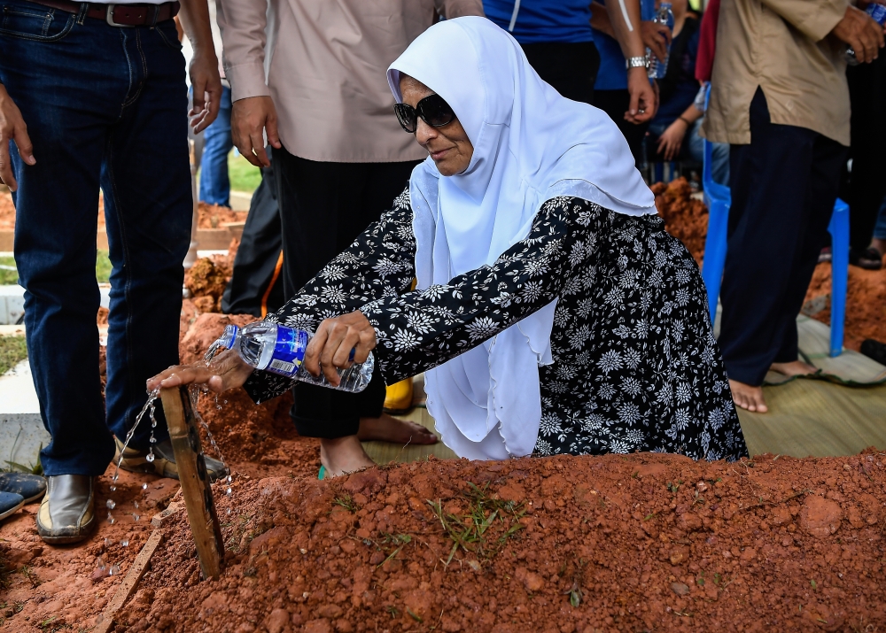 Elmina plane crash victim Mohammad Taufiq Mohd Zaki’s mother Rohani Mohamed Ibrahim sprinkles rose water on his grave at the Ukay Perdana Muslim Cemetery August 20, 2023. — Bernama pic