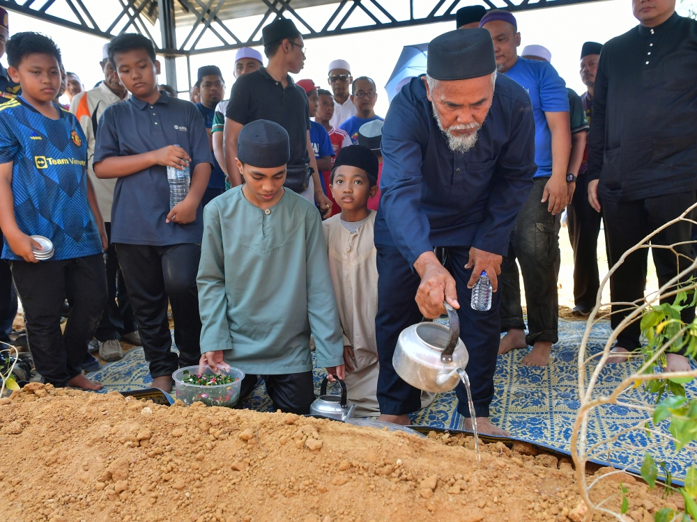 Elmina plane crash victim Khairil Azwan Jamaludin’s father Jamaludin Abd Wahab sprinkles rose water after his burial at the Felda Mempaga 1 Muslim cemetery in Bentong August 20, 2023. — Bernama pic
