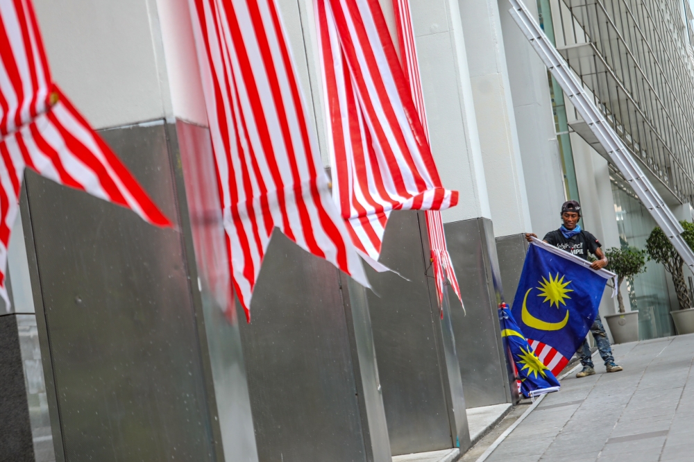 A worker installing the Jalur Gemilang at a government building in Putrajaya in conjunction with the 66th National Day, August 20, 2023. — Picture by Hari Anggara