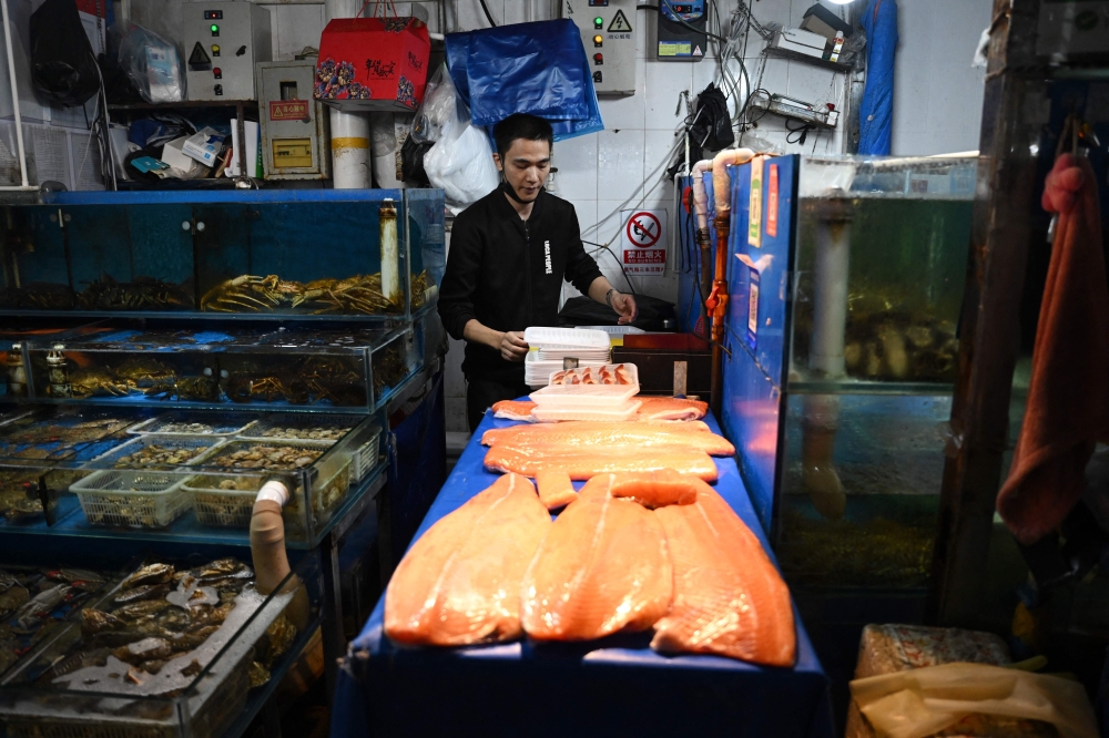 A vendor works in a stall at a wholesale fish market in Beijing August 24, 2023. — AFP pic