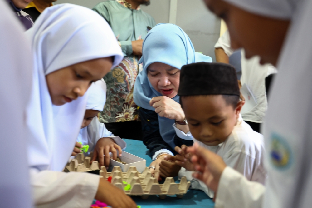 Education Minister Fadhlina Sidek helps students at the Human Capital Development Centre to complete their assignments during her visit to the centre in Semporna, August 25, 2023. — Bernama pic 