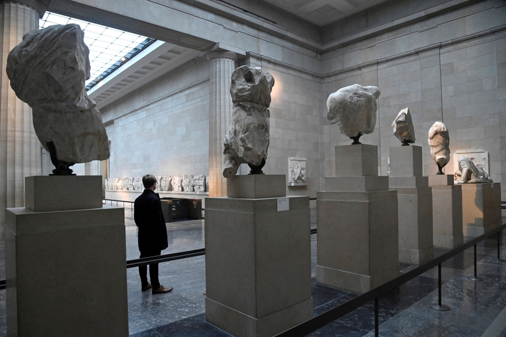 An employee poses as he views examples of the Parthenon sculptures, sometimes referred to in the UK as the Elgin Marbles, on display at the British Museum in London January 25, 2023. — Reuters pic