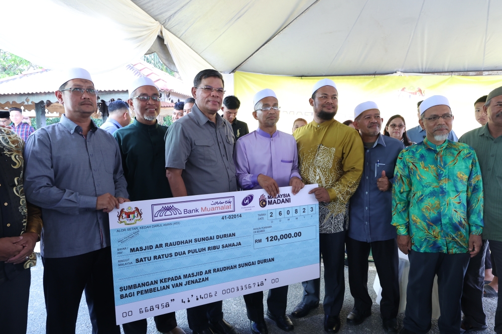 Home Minister Datuk Seri Saifuddin Nasution Ismail (third from left) presents a mock cheque to the Imam of Masjid Ar Raudhah, Ahmad Sayuti Ayob (fourth from right), as a donation from the ministry, in Pokok Sena August 26, 2023. — Bernama pic