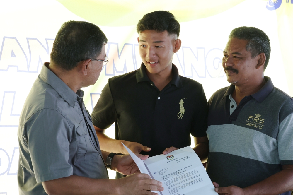 Home Minister Datuk Seri Saifuddin Nasution Ismail (left) presents the citizenship application approval letter to Khatanak Sayyan (centre) at Sungai Durian in Pokok Sena August 26, 2023. — Bernama pic