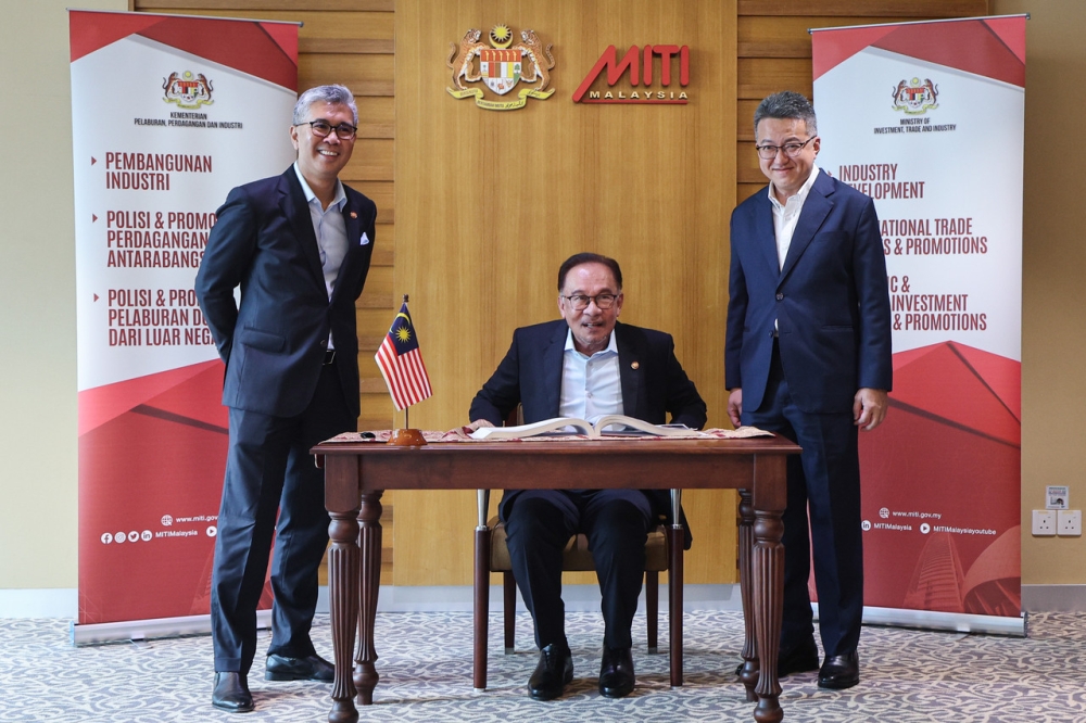 Prime Minister Datuk Seri Anwar Ibrahim signing the visitor's book when he inspects the preparations for the New Industrial Master Plan 2030 (NIMP2030) at the Ministry of Investment, Trade and Industry (MITI) Tower, August 22, 2023. Also present are Minister of International Trade Investment and Industry Tengku Datuk Seri Zafrul Tengku Abdul Aziz (left) and his Deputy Liew Chin Tong (right). — Bernama pic
