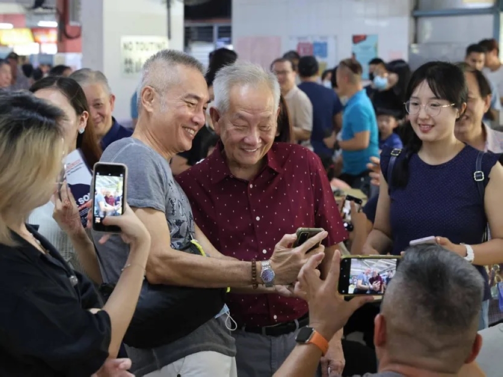Presidential candidate Ng Kok Song (in red shirt) taking photos with residents at Chinatown Complex on Aug 27, 2023. — TODAY pic