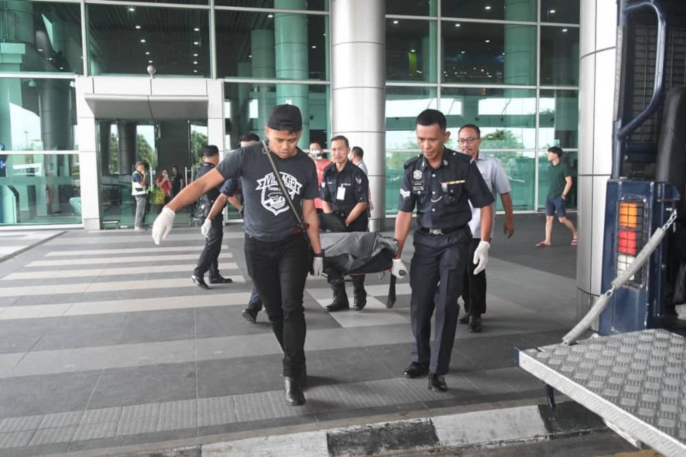 Policemen carry the victim’s body from Kota Kinabalu International Airport. — Borneo Post pic 