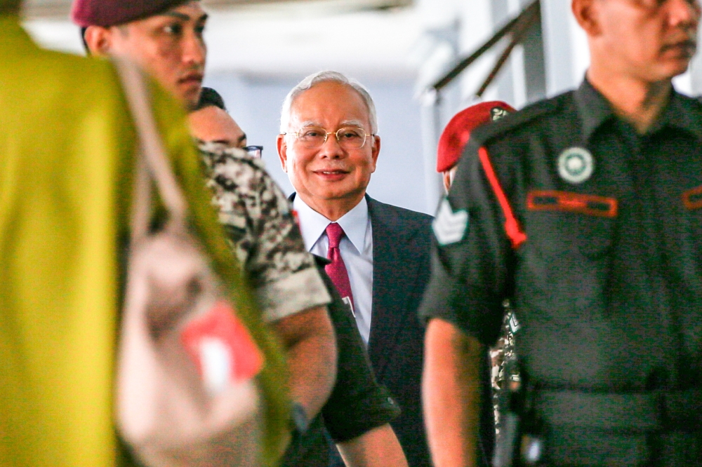 Police officers escort former prime minister Datuk Seri Najib Razak to stand trial at the Kuala Lumpur Court Complex on August 30, 2023. — Picture by Hari Anggara