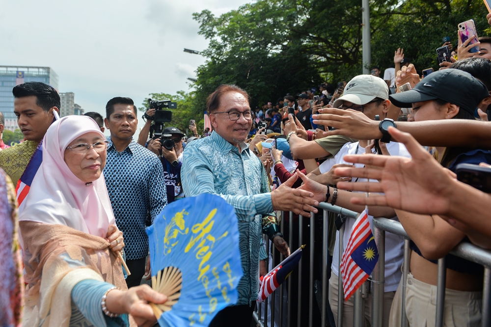 Prime Minister Datuk Seri Anwar Ibrahim and Datuk Seri Dr Wan Azizah Wan Ismail greet the people during National Day celebrations in Putrajaya, August 31, 2023. In a post on Facebook, Anwar hoped the people’s spirit of independence would continue to be strengthened and embedded in all levels of society. — Picture by Miera Zulyana