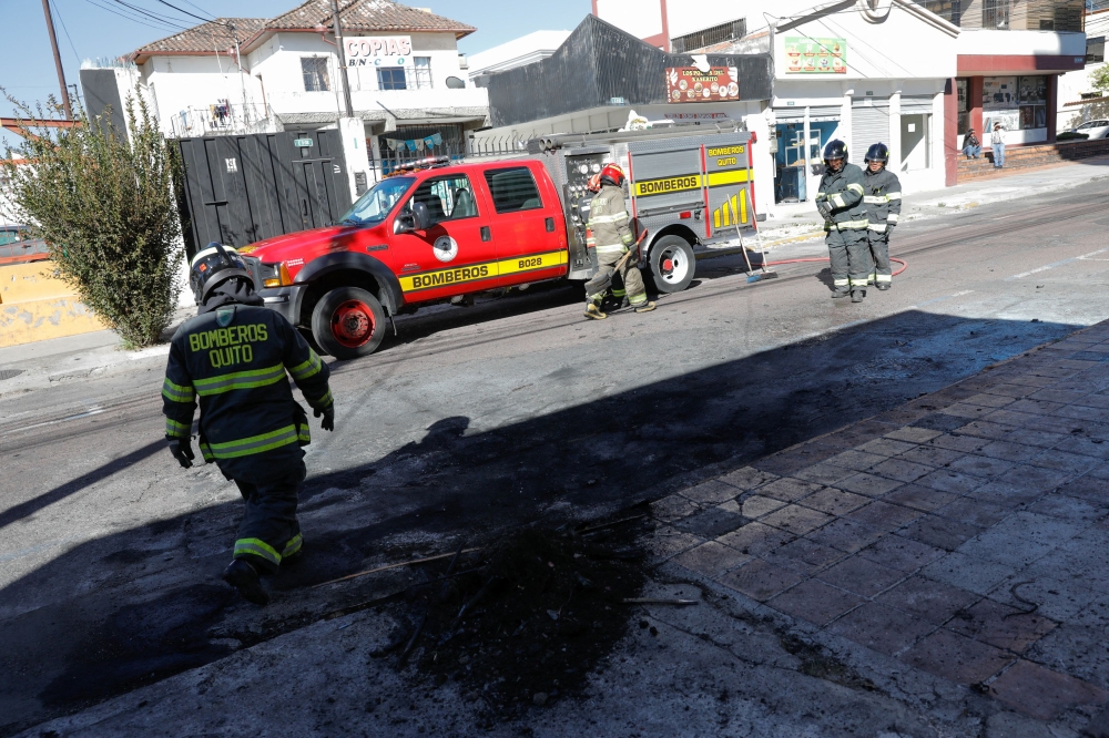 Firefighters work to clean the ashes of a car, that according to authorities was loaded with two gas tanks and later exploded when suspects set it on fire, seemingly targeting Ecuador's prison agency SNAI, in front of the Ministry of Women and Human Rights in Quito, Ecuador August 31, 2023. — Reuters pic