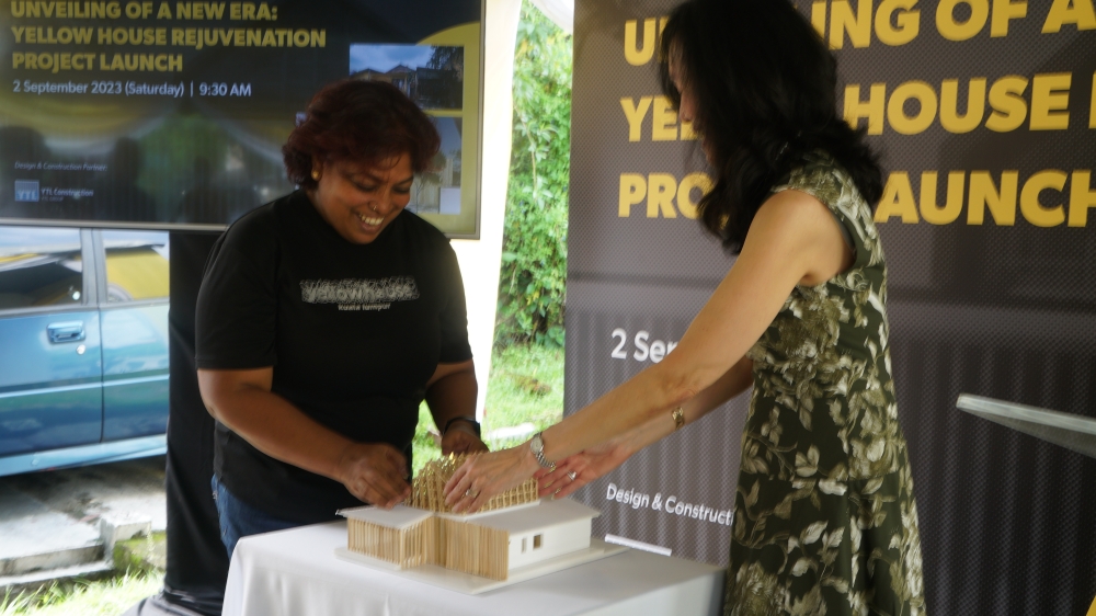 Shyam and Chew installing the bamboo roof on the miniature Yellow House model. — Picture courtesy of YTL Foundation 