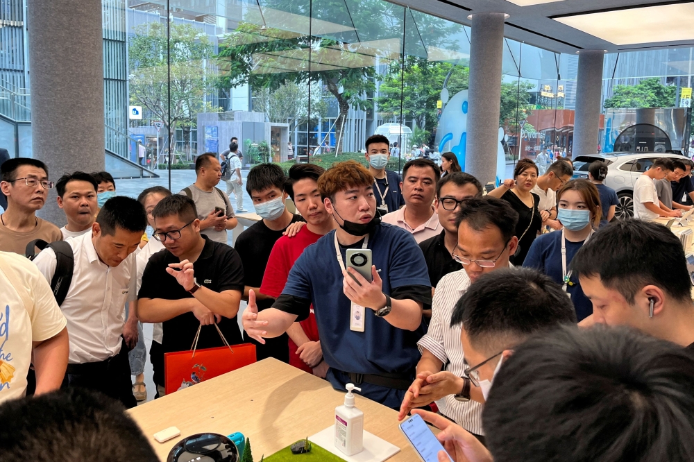 A staff member introduces the new Huawei Mate 60 smartphone to customers at the Huawei flagship store in Shenzhen, Guangdong province, China August 30, 2023. — Reuters pic