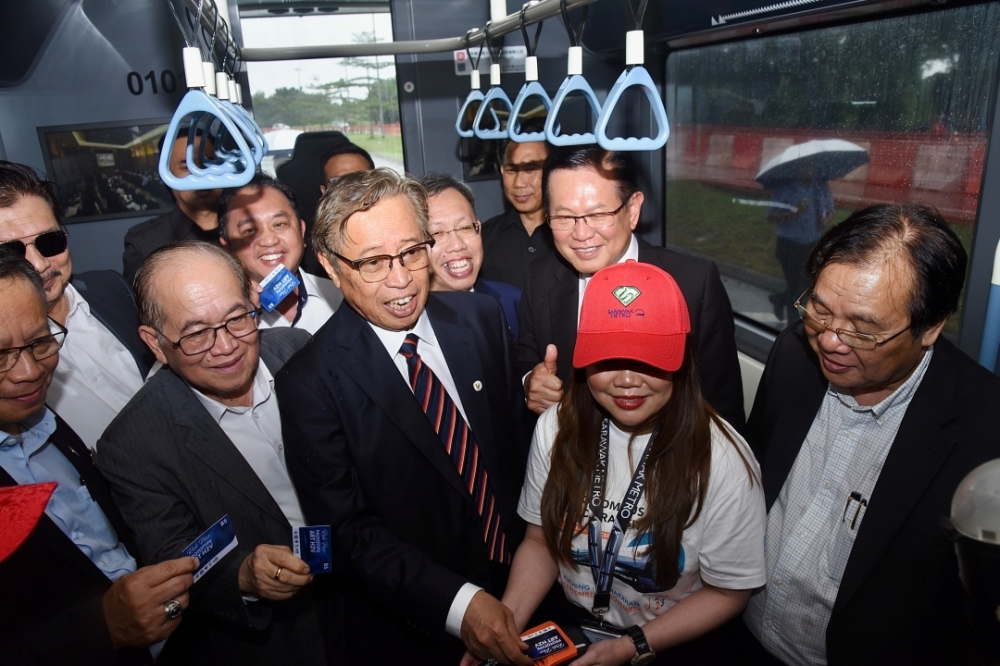 Abang Johari (centre) scans his fare pass as he boards for the hydrogen-powered ART prototype vehicle. — Photo by Information Department