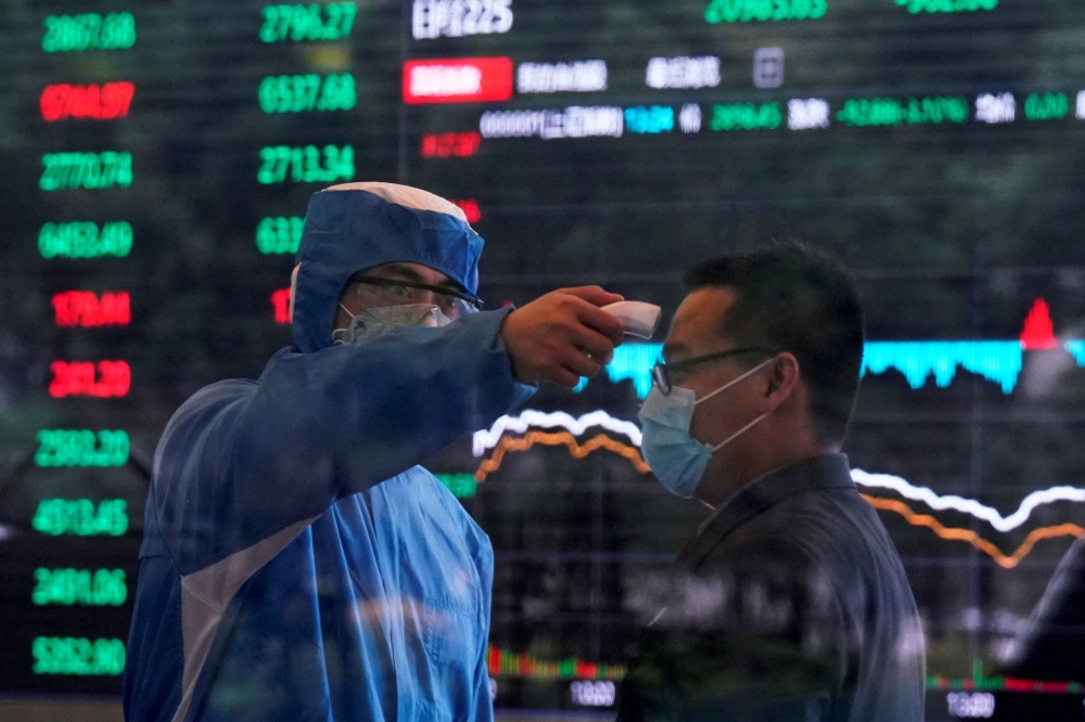 A worker wearing a protective suit takes body temperature measurement of a man inside the Shanghai Stock Exchange building, as the country is hit by a new coronavirus outbreak, at the Pudong financial district in Shanghai February 28, 2020. — Reuters pic