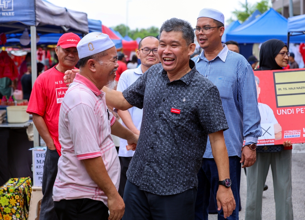 Simpang Jeram by-election candidate from Pakatan Harapan Nazri Abdul Rahman greets members of the public during a walkabout at the Sungai Abong night market in Muar August 29, 2023. — Bernama pic
