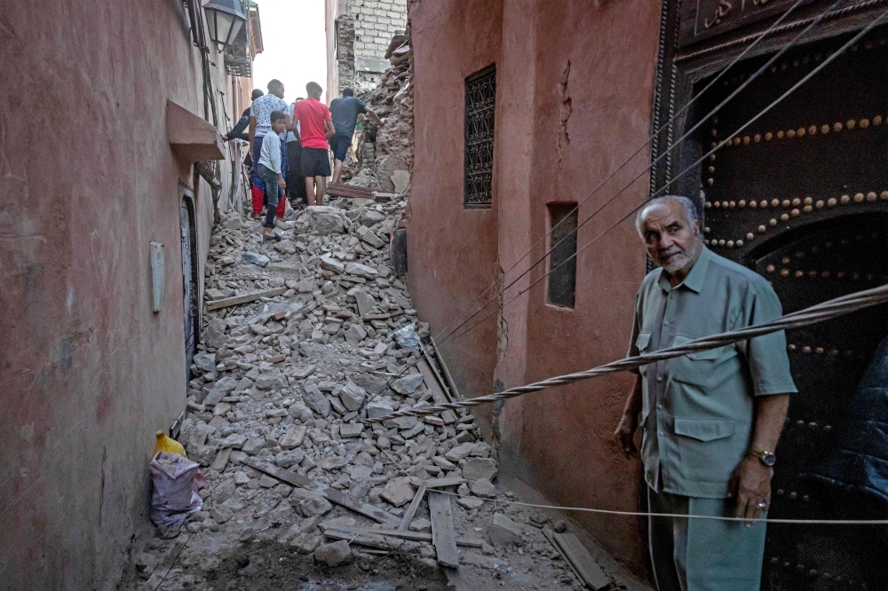 A man looks on as residents navigate through the rubble in the earthquake-damaged old city of Marrakesh on September 9, 2023. — AFP pic