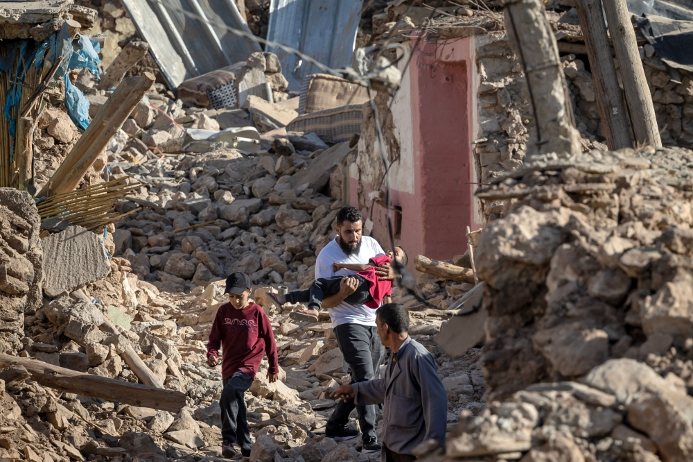 People walk past destroyed houses after an earthquake in the mountain village of Tafeghaghte, south-west of the city of Marrakesh, on September 9, 2023. — AFP pic 